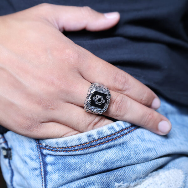 A hand with a black Zenith ring posed in a jeans pocket.