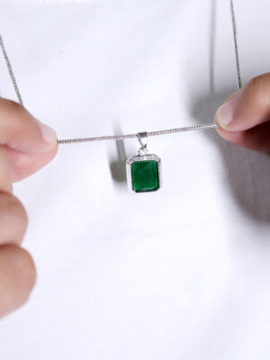 "Man wearing a green stone pendant, holding the pendant with both hands while posing. The vivid green stone stands out as he gently holds it, drawing attention to its bold color and elegant design."