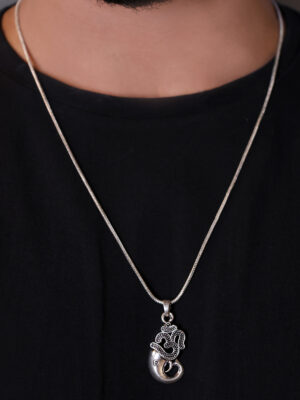 "Man wearing an Om Ganesha pendant with a chain, visible against a black T-shirt. The pendant, featuring a detailed Om symbol integrated with Ganesha's image, stands out prominently against the dark background, highlighting its spiritual significance."