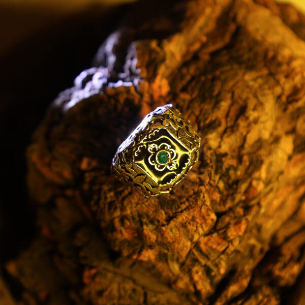 A green Zenith ring placed on natural wood, illuminated by a yellow light from above.